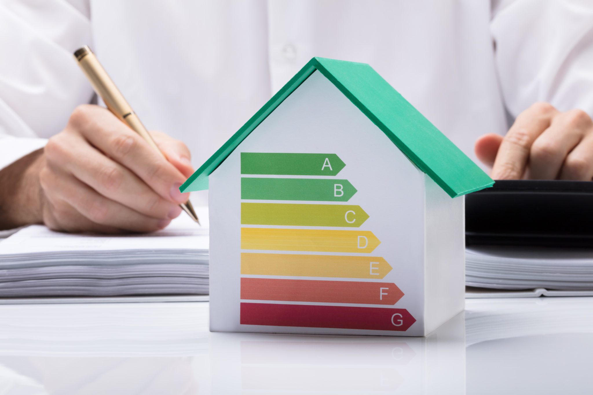 Businessman Calculating Energy Efficient House Midsection Of Businessman Calculating Invoice With Energy Efficient Chart On House Model In Office
